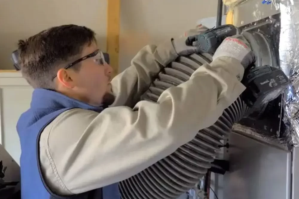 A professional technician performing air duct cleaning to remove dust, debris, and allergens for improved indoor air quality.
